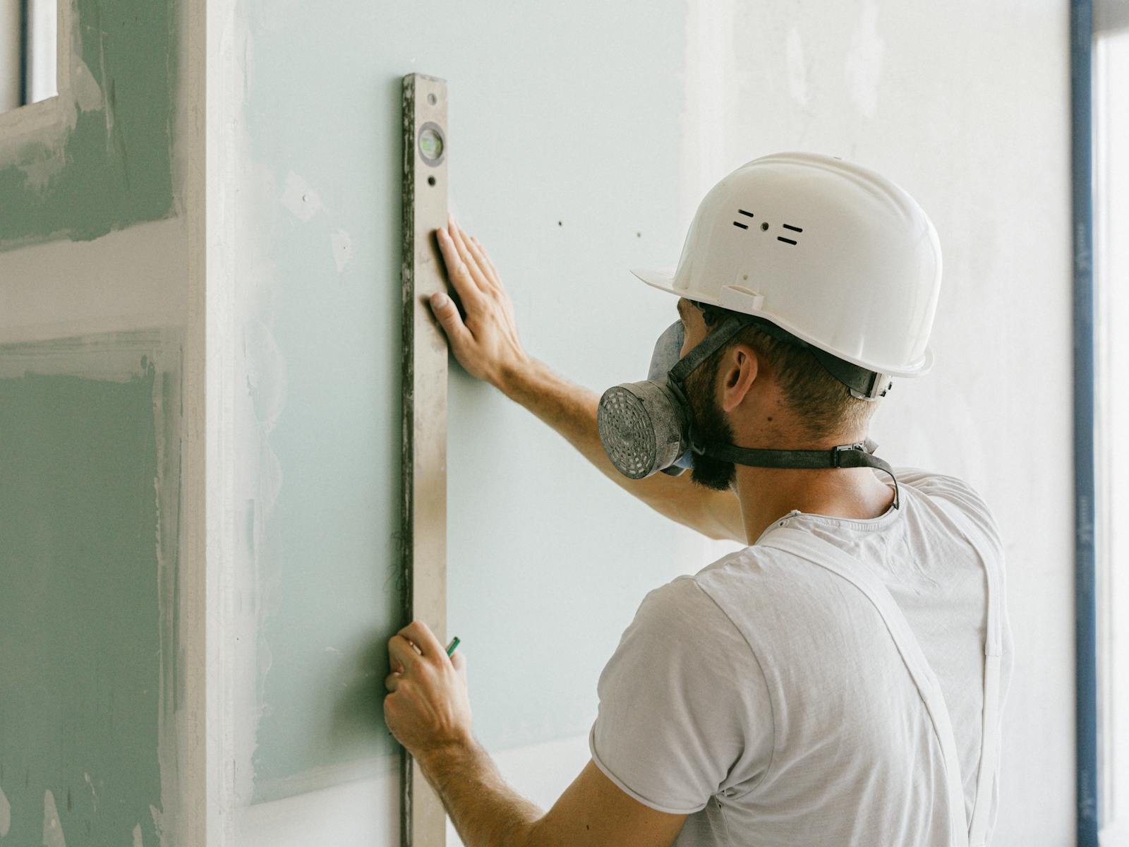 Beyond 9 Interior craftsman checking a drywall partition for plumb on a Denver commercial jobsite